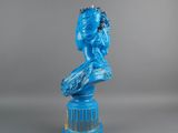 statue of a woman in a blue dress sitting on top of a blue pedestal