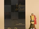 un flacon de parfum et un coffret de parfum posés sur une table, avec un autre coffret de parfum en arrière-plan