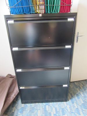 a black filing cabinet with a basket on top of it