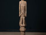 une statue en bois représentant une femme debout sur un piédestal