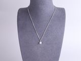 a silver necklace with a white diamond on a mannequin neck