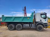 a green dump truck that is parked in the dirt