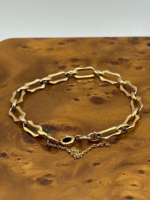 un gros plan d'un bracelet en or posé sur une surface en bois