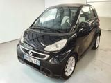 La petite Smart noire est garée dans le garage.