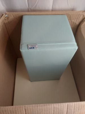 un réfrigérateur bleu dans un carton posé par terre