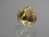un gros plan d'une bague en or et diamants posée sur une surface transparente
