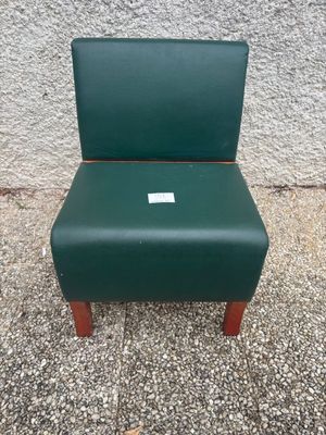 a green chair sitting on top of a sidewalk next to a wall