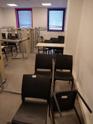 many chairs and tables in a room with a lot of desks