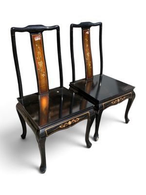 pair of black and gold painted chairs sitting on top of each other