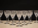 six empty wine glasses lined up on a table with a black background