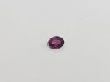 a pink sapphire stone on a white surface