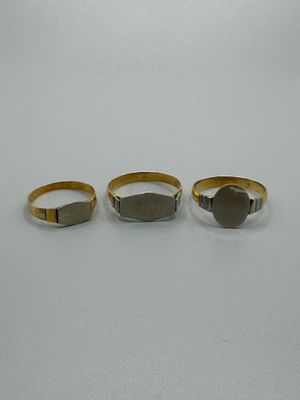 trois bagues en or et en argent sur un fond blanc