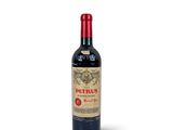 a bottle of red wine sitting on top of a white table