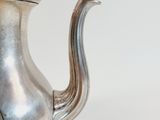 a silver tea pot sitting on top of a table
