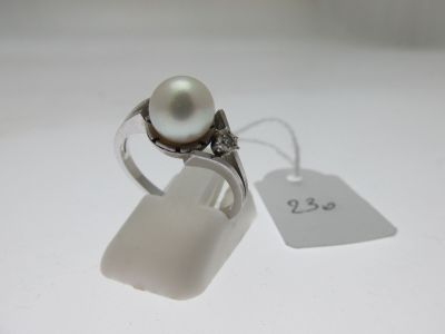 bague en argent ornée d'une perle et d'une petite plaque sur un fond blanc
