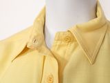 the shirt is yellow and has buttons on the collar