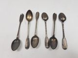 six spoons are lined up in a row on a white surface