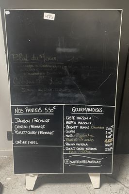 un tableau noir sur lequel est inscrit le menu, posé sur le trottoir
