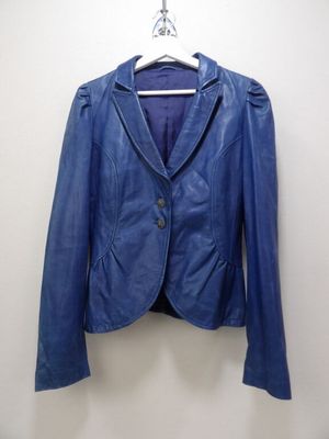 une veste en cuir bleue suspendue à un cintre sur un mur blanc