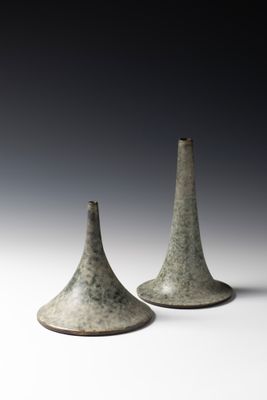une paire de vases gris posés sur une surface blanche