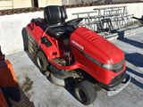 a red riding lawn mower parked on the concrete