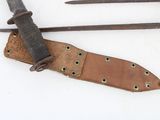 two knives and a sheath on a white surface