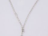 un collier en or blanc orné d'un pendentif en forme de croix sertie de diamants, sur fond blanc