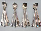 four forks and a spoon are lined up on a table