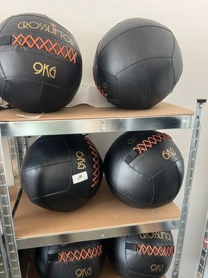 Trois ballons médicinaux en cuir noir sont posés sur une étagère dans une pièce