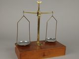 une image représentant une balance sur laquelle sont posées deux assiettes argentées