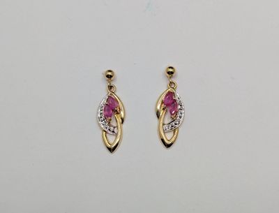 une paire de boucles d'oreilles en diamants roses et blancs posées sur une surface blanche