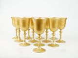 six coupes en or sont alignées sur une surface blanche