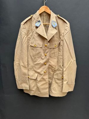 une photo d'une veste beige accrochée à un mur noir