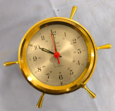 une horloge dorée avec des aiguilles rouges sur un fond blanc