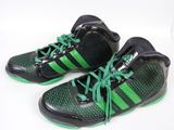 une paire de baskets noires et vertes avec des lacets verts sur un fond blanc