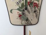 an image of a fan with flowers on it hanging on a wall