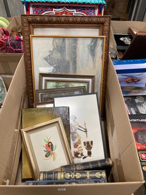 une boîte remplie d'œuvres d'art variées, encadrées ou non