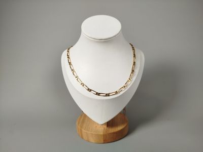collier à chaîne en or posé sur un présentoir à mannequin, sur fond gris