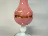 a pink glass vase with a gold rim on a white table