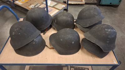 six helmets are on a cart in a warehouse with other items