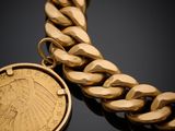 a close up of a gold chain bracelet with a coin on it