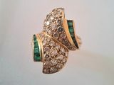 une photo d'une bague sertie d'un diamant et d'une émeraude sur un fond blanc