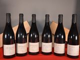 six bottles of red wine are lined up on a table