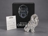 a silver figurine of a lion sitting next to a business card