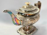 a silver teapot with a bird on top of it