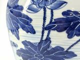 a blue and white vase with flowers and leaves on it