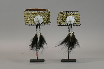 two lamps with black and white feathers on them on a stand