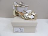 gold and white high heeled sandals on a box on a table