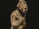 statue of a man sitting on his knees with his hands clasped