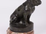 une statue représentant un chien assis sur un socle en marbre